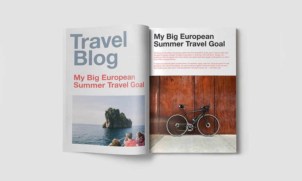 An open magazine with the title "Travel Blog" and the headline "My Big European Summer Travel Goal." The left page shows a small rock island with greenery in blue water, while the right page features a black bicycle against a brown, textured wall. Discover travel tips on our mobile app!